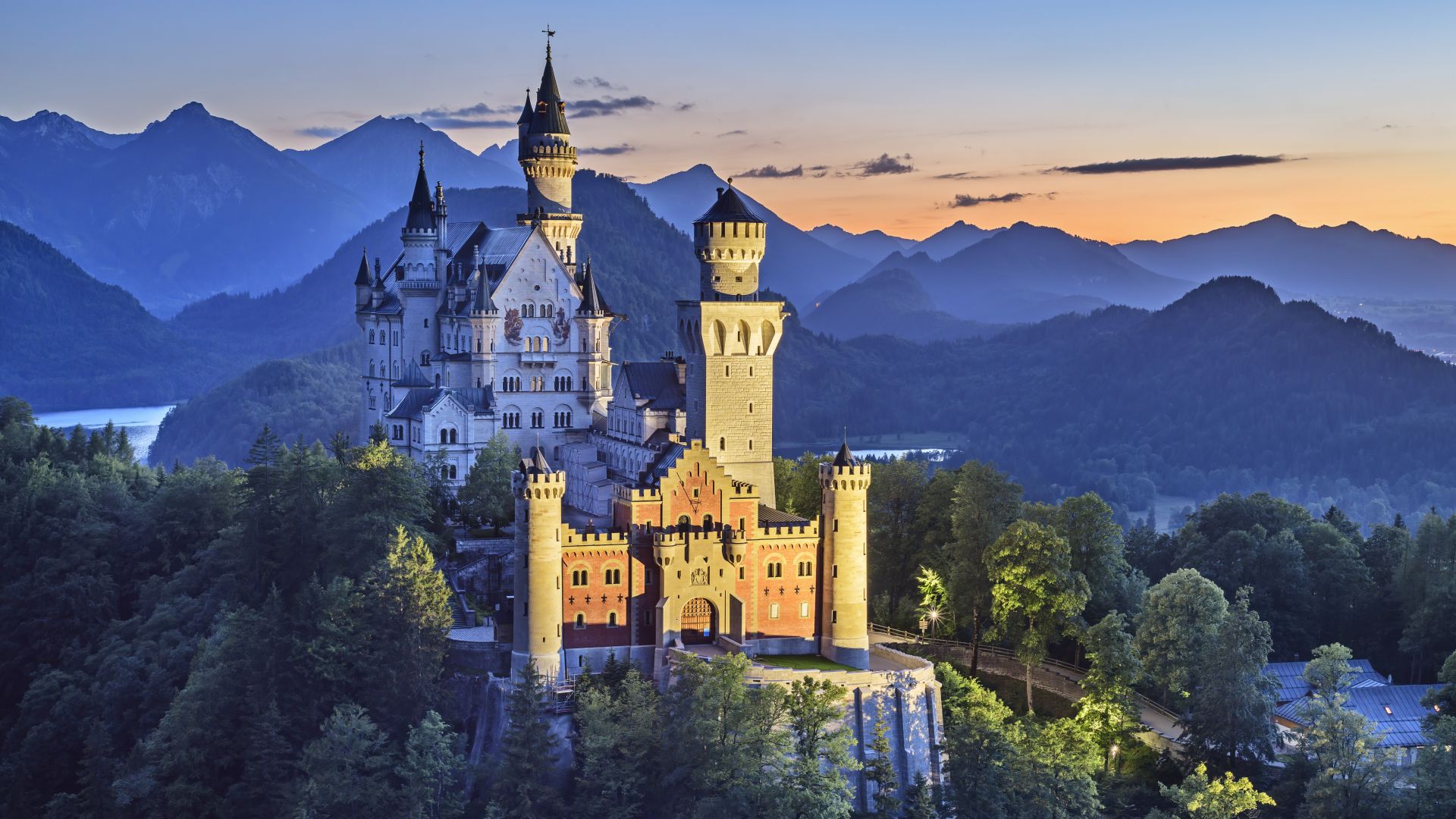 Schwangau: Neuschwanstein Castle illuminated at dusk in front of the Tannheimer Mountains, Ammergau Alps